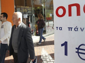 Unos peatones pasan al lado de una tienda de "todo a un euro" en Atenas