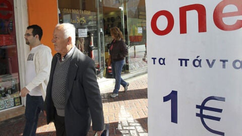 Unos peatones pasan al lado de una tienda de "todo a un euro" en Atenas
