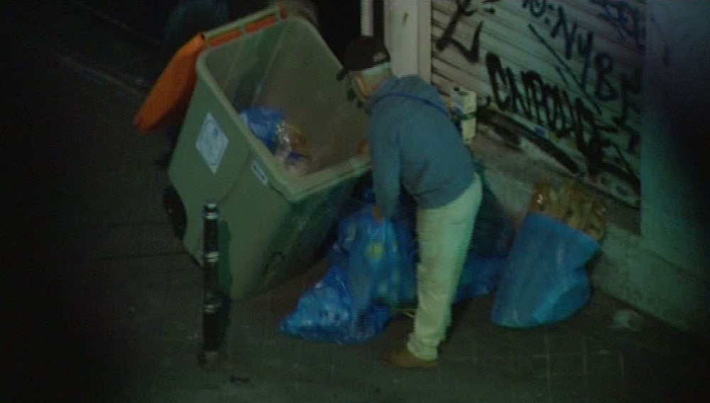 Un hombre recoge comida de la basura