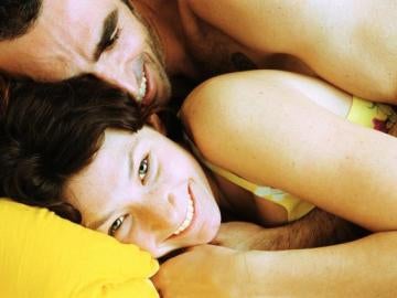 Una pareja bromea tumbada en una cama Una pareja bromea tumbada en una cama