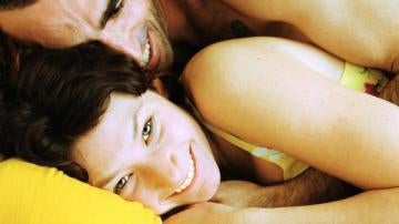 Una pareja bromea tumbada en una cama