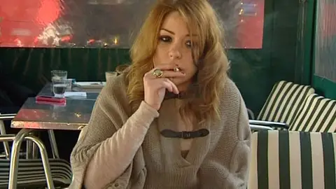 Una joven fuma en la terraza de un restaurante Una joven fuma en la terraza de un restaurante