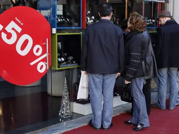 Varias personas delante de un escaparate en rebajas Varias personas delante de un escaparate en rebajas