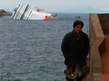 Una mujer en la isla de Giglio con el crucero Costa Concordia a su espalda Una mujer en la isla de Giglio con el crucero Costa Concordia a su espalda