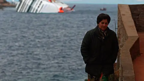 Una mujer en la isla de Giglio con el crucero Costa Concordia a su espalda Una mujer en la isla de Giglio con el crucero Costa Concordia a su espalda