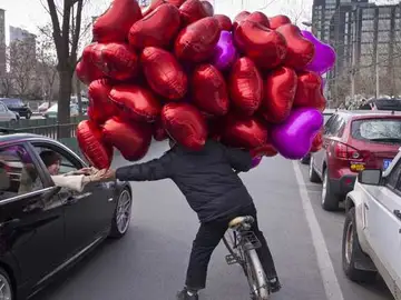 Un comerciante vende globos de corazón en Pekín Un comerciante vende globos de corazón en Pekín