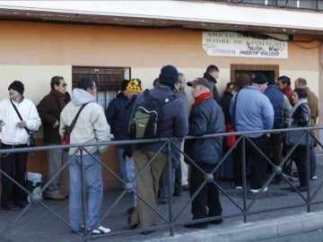 Un grupo de personas guarda cola para entrar en un comedor social