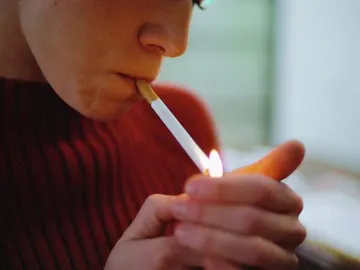 Una mujer encendiendo un cigarrillo Una mujer encendiendo un cigarrillo