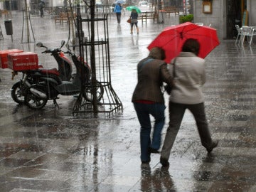 Dos mujeres se protegen con un paraguas de un chaparrón en Madrid