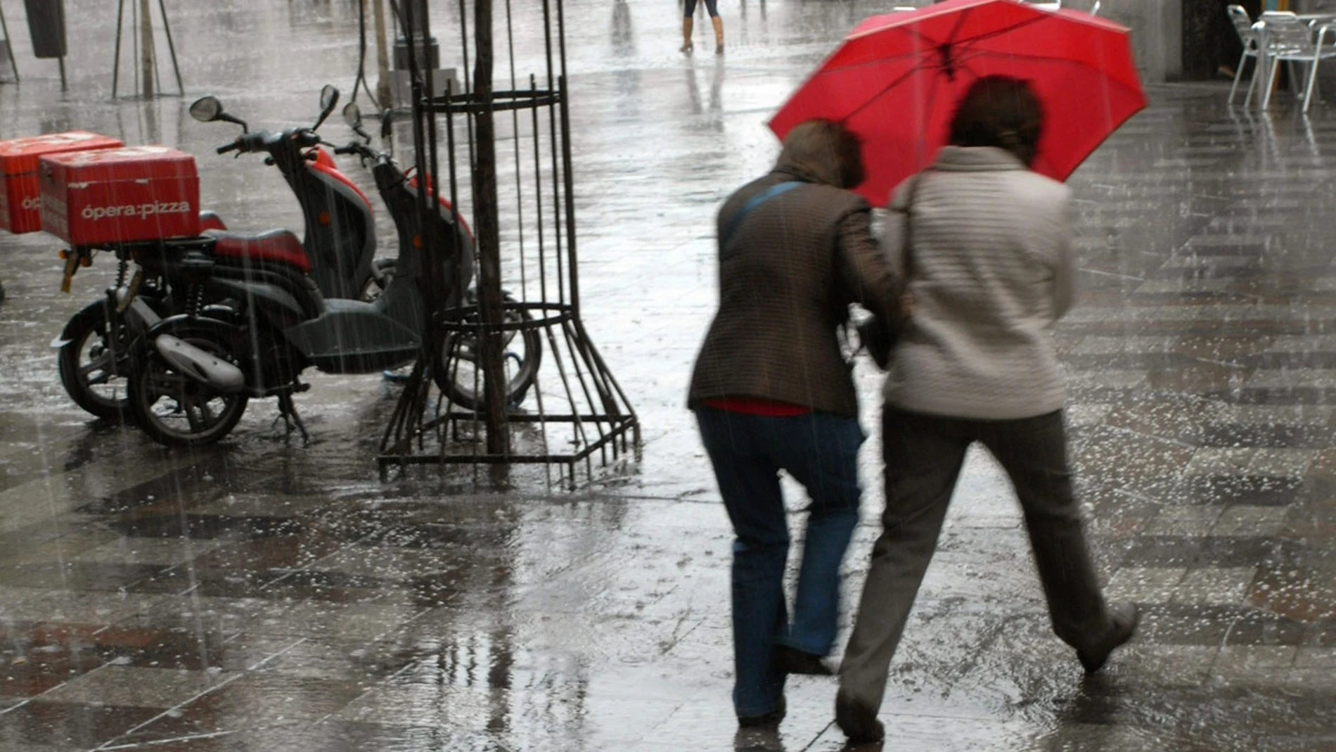 Dos mujeres se protegen con un paraguas de un chaparrón en Madrid