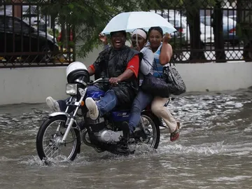 Tres personas se desplazan bajo la lluvia en Santo Domingo. Tres personas se desplazan bajo la lluvia en Santo Domingo.