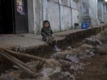 Un niño espera sentado entre los escombros en Guatemala