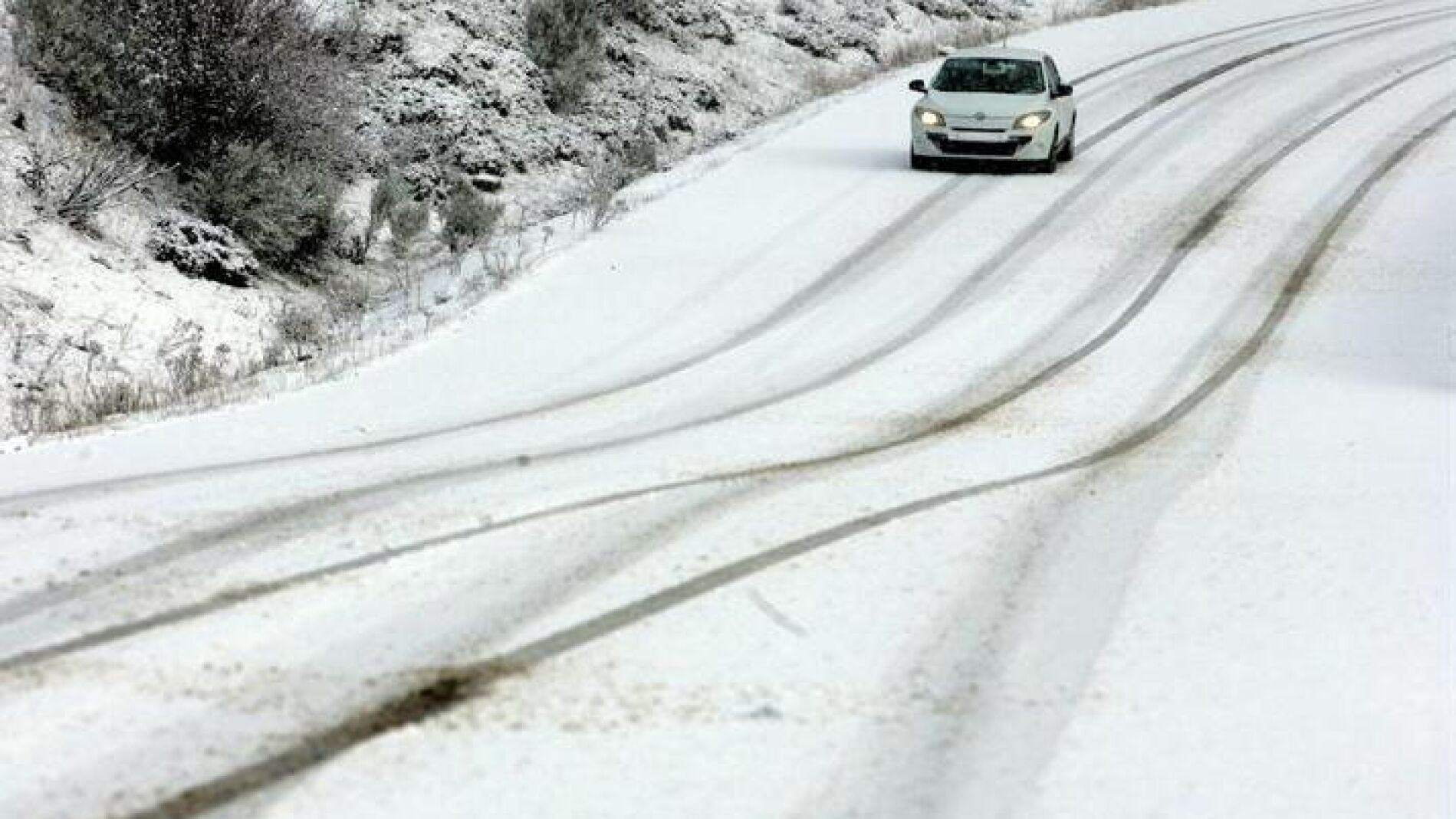 Un veh&iacute;culo circula por el puerto de San Isidro (Le&oacute;n) durante la nevada registrada en la regi&oacute;n