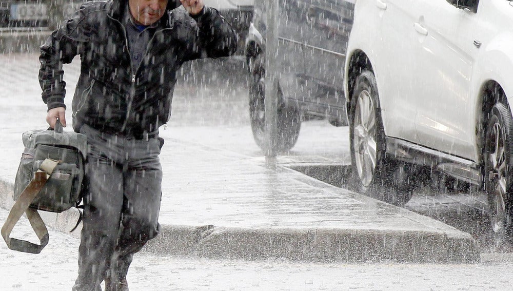 Un hombre corre durante la tormenta registrada hoy en Santander 