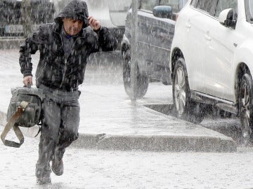 Un hombre corre durante la tormenta registrada hoy en Santander 