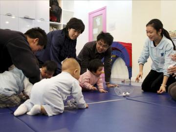 Varios padres juegan con sus bebés durante una clase para los pequeños en un colegio en Shanga