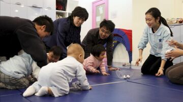 Varios padres juegan con sus bebés durante una clase para los pequeños en un colegio en Shanga