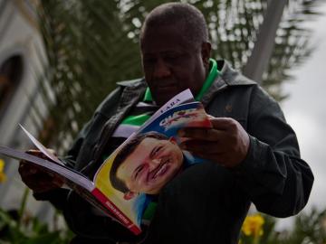 Un hombre sostiene un libro con la imagen del presidente Hugo Chávez 