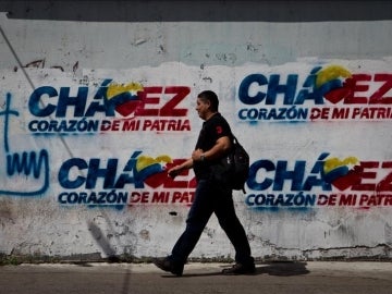  Transeúntes caminan frente a paredes decoradas con grafitis alusivos al presidente Hugo Chávez.
