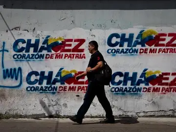 Transeúntes caminan frente a paredes decoradas con grafitis alusivos al presidente Hugo Chávez. Transeúntes caminan frente a paredes decoradas con grafitis alusivos al presidente Hugo Chávez.