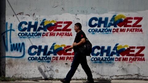  Transe&uacute;ntes caminan frente a paredes decoradas con grafitis alusivos al presidente Hugo Ch&aacute;vez.