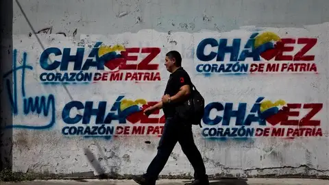 Transeúntes caminan frente a paredes decoradas con grafitis alusivos al presidente Hugo Chávez. Transeúntes caminan frente a paredes decoradas con grafitis alusivos al presidente Hugo Chávez.