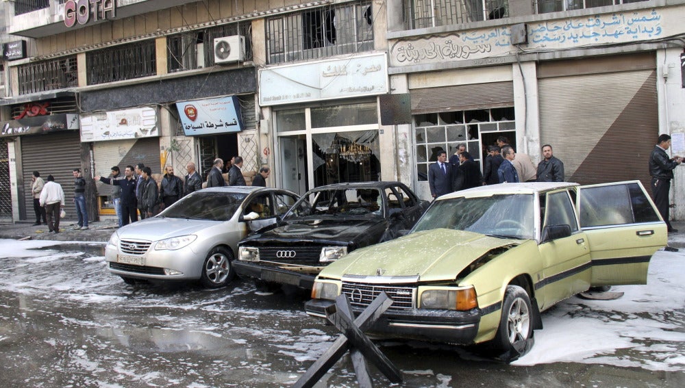 Varias persoans observan los destrozos en una calle en Damasco (Siria)