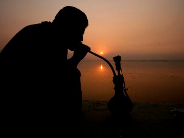 Un hombre fumando una pipa de agua Un hombre fumando una pipa de agua