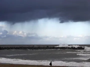 Un hombre camina por la playa de la Zurriola de San Sebastián Un hombre camina por la playa de la Zurriola de San Sebastián