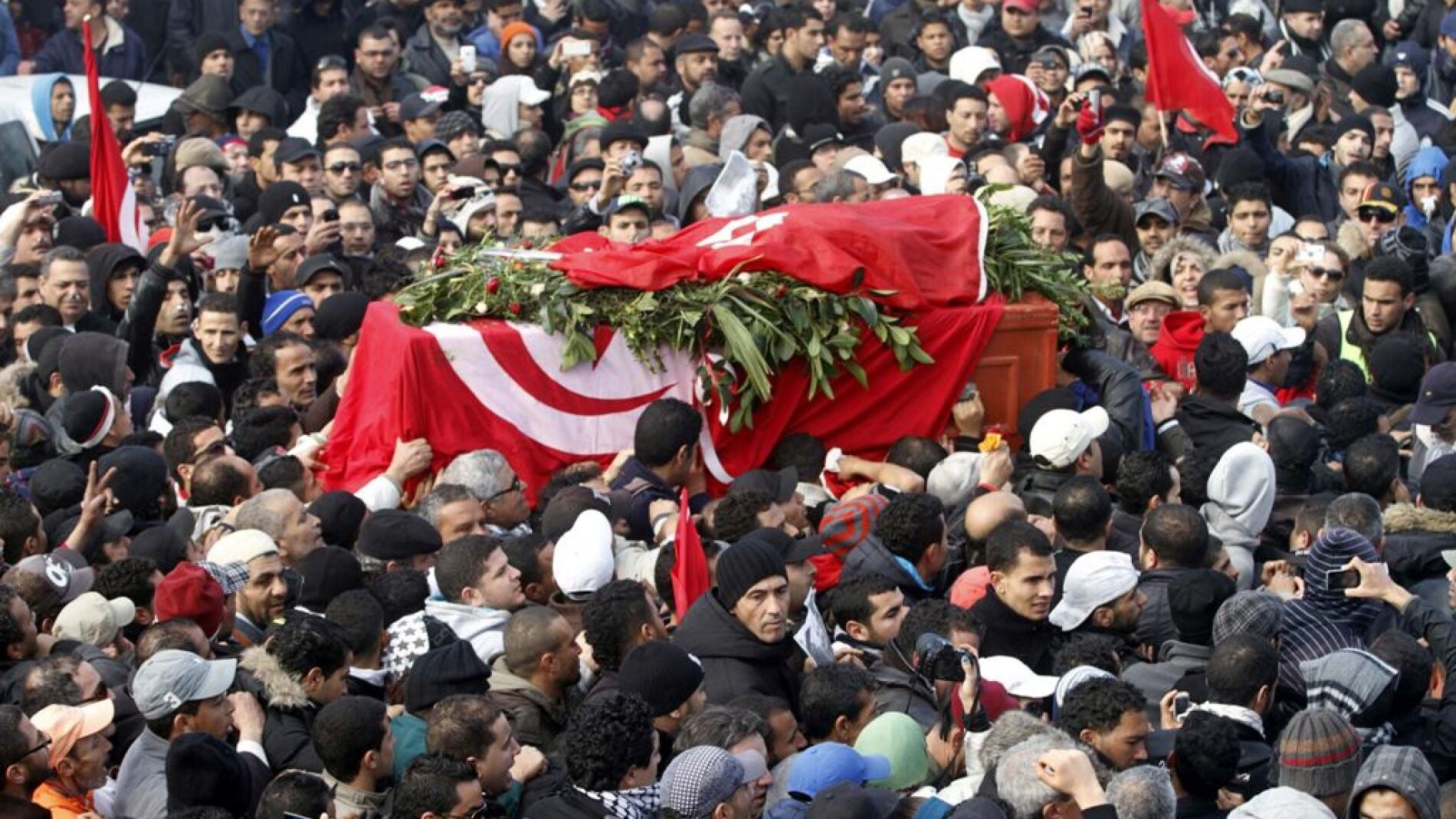 Varias personas portan el f&eacute;retro del pol&iacute;tico opositor tunecino Chukri Bel Aid
