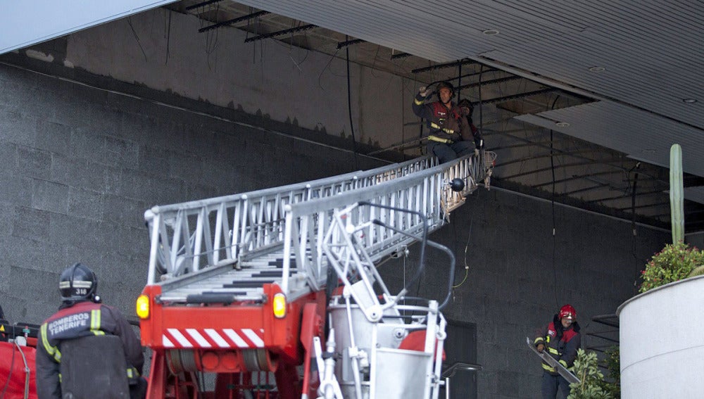 Unos bomberos de Santa Cruz de Tenerife retiran esta tarde algunas planchas de un falso techo 