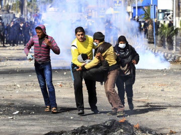 Manifestantes egipcios trasladan a un compañero herido