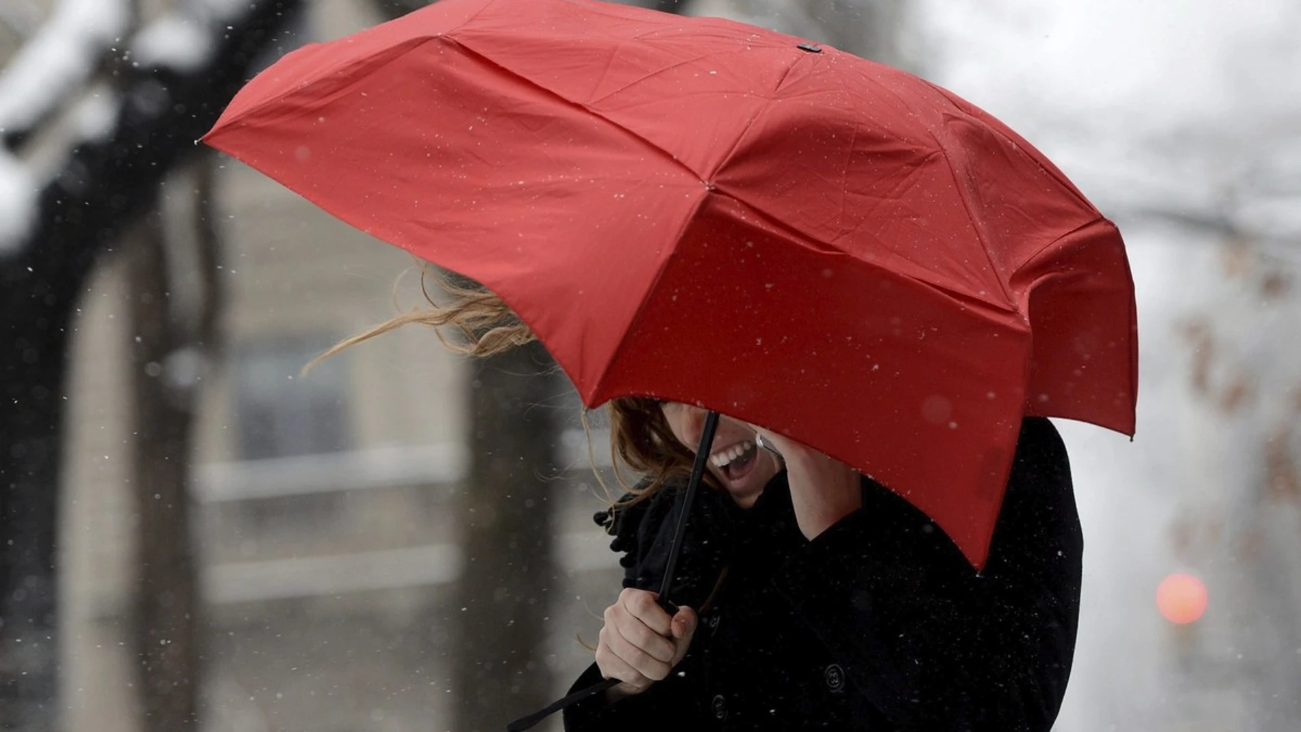 Una mujer habla por su teléfono móvil tratando de protegerse del viento Una mujer habla por su teléfono móvil tratando de protegerse del viento