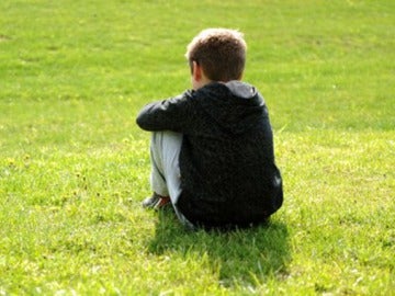 Imagen de archivo de un niño sentado en el césped.