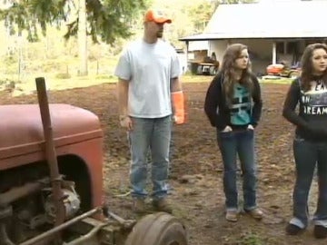 Las hermanas Haylee y Hannah Smith, junto a su padre Jeff y el tractor que levantaron