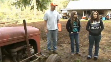 Las hermanas Haylee y Hannah Smith, junto a su padre Jeff y el tractor que levantaron