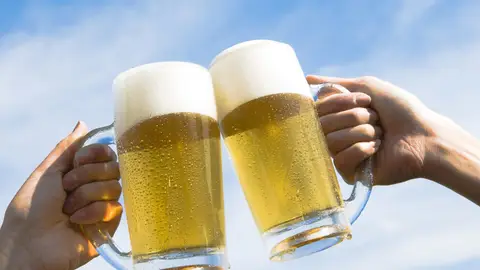 Dos personas brindan con cerveza Dos personas brindan con cerveza