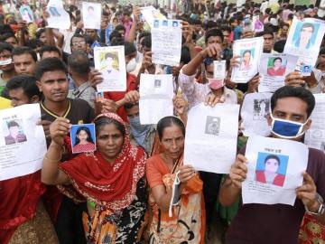 Familiares de las víctimas muestran imágenes de las personas fallecidas por el derrumbe en Bangladesh