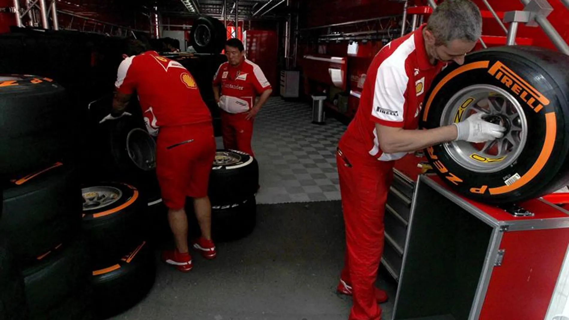Mecánicos del equipo Ferrari trabajan con los neumáticos 