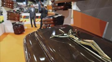 Un vendedor muestra a dos clientes diferentes modelos de ataúdes en Funermostra
