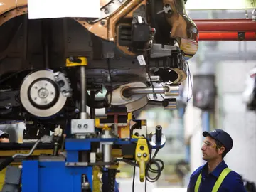 Un trabajador en la cadena de montaje de Ford Un trabajador en la cadena de montaje de Ford