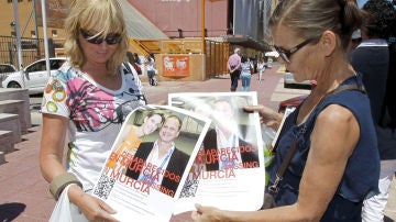 Dos ciudadanas muestran la foto de los desaparecidos