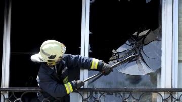 Un efectivo del cuerpo de Bomberos rompe una ventana durante un incendio en Getxo.