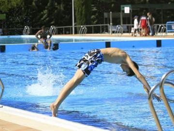 Un joven se lanza al agua en el primer día de apertura de las piscinas madrileñas