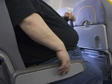 Un pasajero con sobrepeso en un viaje en avión Un pasajero con sobrepeso en un viaje en avión