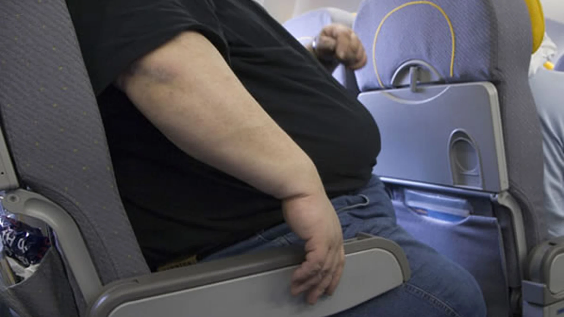 Un pasajero con sobrepeso en un viaje en avión Un pasajero con sobrepeso en un viaje en avión