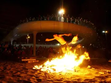 Varias personas observan una de las hogueras encendidas en una playa. Varias personas observan una de las hogueras encendidas en una playa.