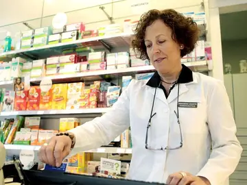 Una mujer atendiendo en una farmacia Una mujer atendiendo en una farmacia
