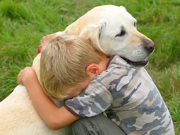 Un niño abraza a su perro Un niño abraza a su perro