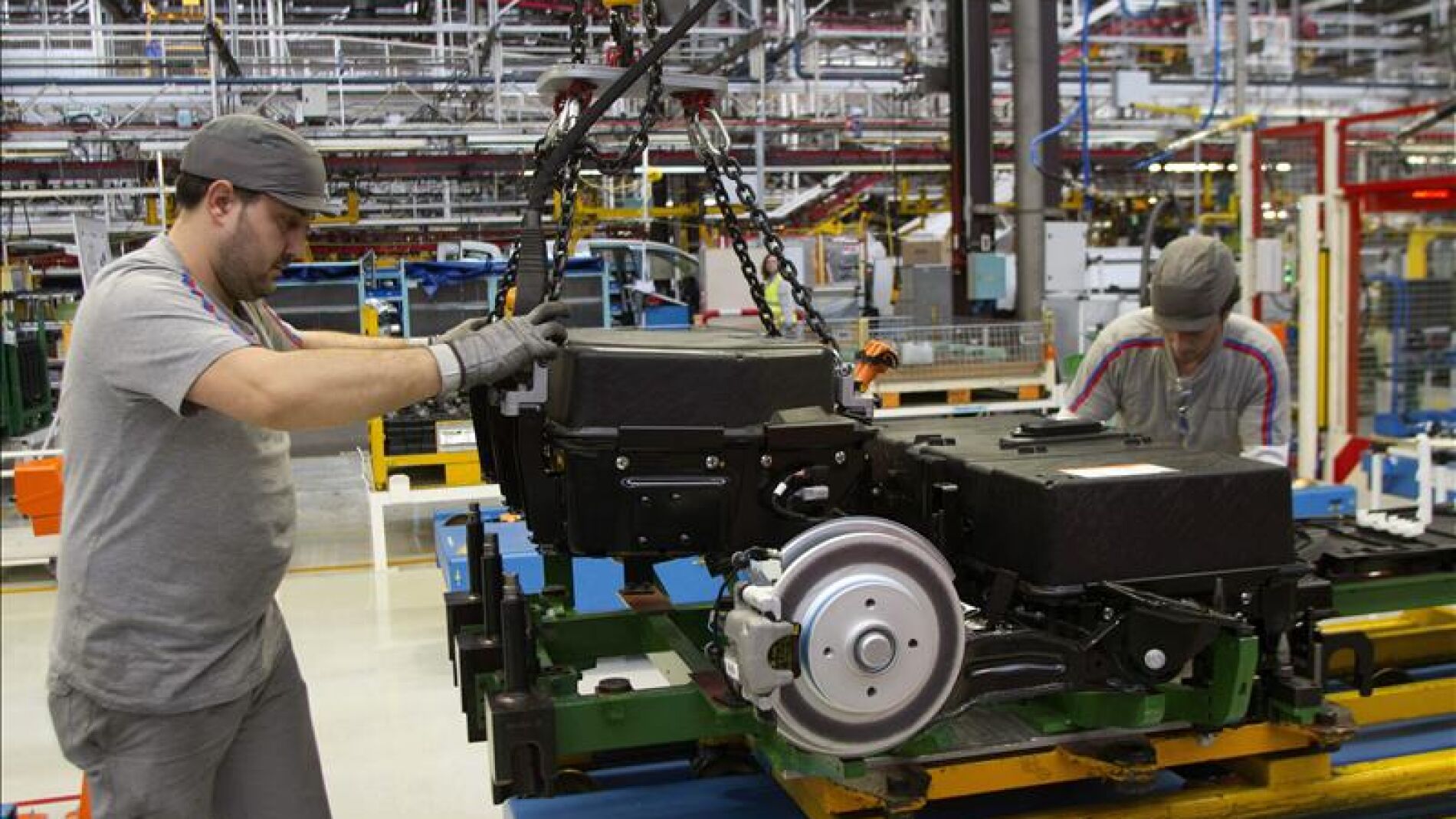 Dos operarios colocan bater&iacute;as en un autom&oacute;vil